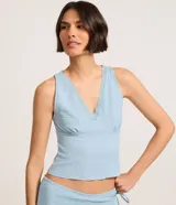 Blusa musculosa celeste confeccionada en anarruga, con escote en V y detalle de encaje.