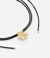 Collar choker con cordón negro ajustable y colgante de flor dorada.