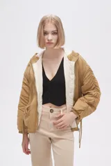 Campera negra de manga larga con capucha, cierre frontal con botones a presión, bolsillos laterales y cordón ajustable en la cintura.