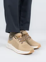 Zapatilla acordonada de cuero color beige con perforaciones en los laterales y suela blanca con base de goma color caramelo.
