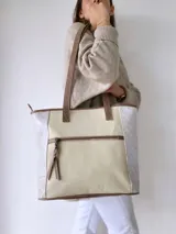 Bolso tipo tote bag color beige con laterales estampados y detalles en cuero marrón.