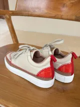 Championes de cuero color beige con puntera de gamuza marrón y costuras rojas.