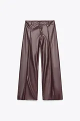 Pantalón marrón de tiro alto con efecto cuero, bolsillos de parche en la parte trasera y costuras marcadas en la parte delantera. Cierre frontal con cremallera y gancho metálico.