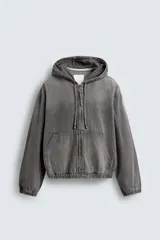 Cazadora gris de algodón con efecto lavado, corte relaxed fit, cuello con capucha ajustable, manga larga, bolsillos frontales tipo canguro, acabados con elástico y cierre frontal de cremallera.