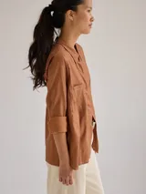 Camisa color marrón de lino y viscosa, de corte clásico, con cuello camisero, cierre frontal con botones, mangas largas con puños abotonados y dos bolsillos de parche en el pecho.