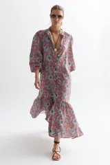 Vestido midi de lino color ladrillo con estampado floral celeste, corte recto, cuello mao, mangas abullonadas 3/4 con puños elásticos, cierre frontal con botones y falda con volantes.