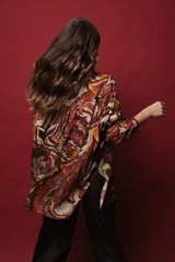 Camisa de seda de algodón estampada con arabescos en tonos marrones, verdes, naranjas y dorados. Tiene corte holgado, abertura frontal y lurex dorado.