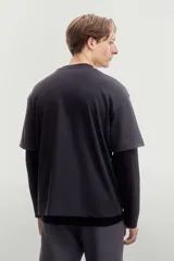 Remera negra de algodón pesado, corte holgado, con cuello redondo ribeteado, hombros caídos y bajo recto.