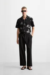 Camisa negra con estampado floral en tonos grises, de manga corta y cuello bowling.