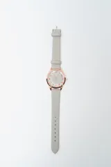 Reloj analógico con caja redonda color oro rosado, esfera blanca con números arábigos en color oro rosado y correa de cuero blanco texturizado.