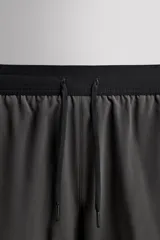 Shorts deportivos color verde oliva confeccionados en tejido técnico ligero y elástico. Cuenta con forro interior, cintura elástica ajustable con cordón, bolsillos laterales, bolsillo de seguridad en espalda con cierre de cremallera, bajo con aberturas laterales y logo estampado en la pierna.