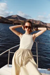 Vestido midi color beige con top blanco de cuello redondo y manga sisa con vivos negros a contraste. Cintura elástica y falda con aberturas laterales.