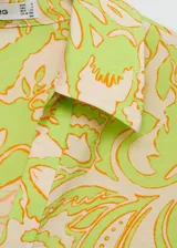 Camisa de manga corta con estampado floral en tonos verde, naranja y beige. Diseño oversize con cuello camisero y cierre frontal con botones.