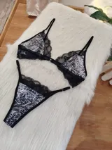 Conjunto de lencería compuesto por un corpiño triangular sin aro con estampado animal print y detalles de encaje negro, y una bombacha tipo colaless con el mismo estampado y borde de encaje negro. El corpiño tiene cierre frontal.