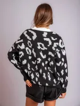 Sweater de punto negro con estampado animal print en blanco y cuello redondo blanco.