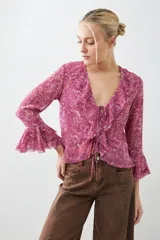 Blusa fucsia estampada con volados, escote en V y mangas largas acampanadas.