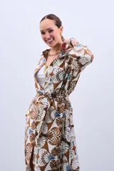 Camisola tipo vestido con estampado floral en tonos marrón, beige y celeste. Tiene cuello camisero, mangas largas y lazo para ajustar en la cintura.