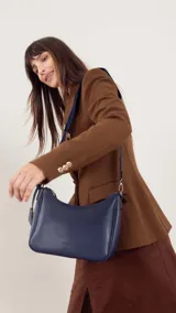 Bandolera morral negra de símil cuero, con cierre trasero y división interna. Incluye correa de galón ajustable.