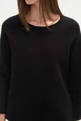 Sweater blanco liso, de corte holgado, con cuello a la base y broches decorativos en los laterales.