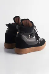Zapatilla urbana negra de caña alta con plataforma, cordones y detalles de cuero y gamuza.