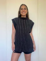 Chaleco tejido con hilo de algodón y lurex en punto acanalado vertical, corte recto con pequeños tajos laterales, cuello redondo con guarda ancha y hombros amplios.