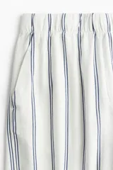 Pantalón capri de corte amplio con cintura elástica y estampado a rayas verticales azules sobre fondo blanco.