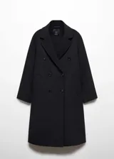 Abrigo largo negro oversize con doble botonadura, solapas con muesca, hombros caídos, bolsillos laterales y abertura posterior.