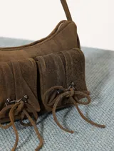 Cartera tipo bandolera color gris oscuro, realizada en cuero ovino, con cierre metálico y forro de poliéster jacquard. Tiene doble bolsillo frontal con cierre imantado y apliques metálicos níquel. Incluye correa corta de cuero para usar al hombro.