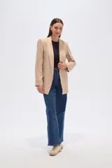 Blazer color beige, de corte holgado, con solapas anchas y bolsillos frontales.