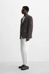 Blazer marrón con estampado pata de gallo, de corte regular fit, con cuello de solapas de muesca, manga larga con puños abotonados, bolsillo de vivo en el pecho, bolsillos de solapa en la cadera, bolsillo interior, aberturas en la espalda y cierre frontal con botones.