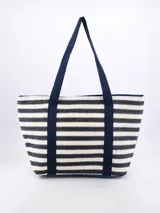 Bolso tote de paja con rayas horizontales en blanco y negro, con asas de tela azul marino.