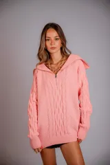 Buzo de punto color rosado, con cuello polo y cierre frontal parcial, de manga larga y diseño holgado.