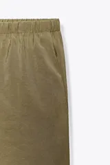 Pantalón palazzo color verde oliva de tejido fluido, tiro medio, cintura elástica ajustable con cordones y bolsillos laterales.