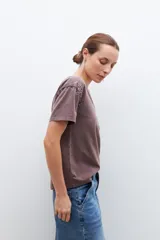 Remera gris oscuro con cuello en V y tachas plateadas en los hombros.