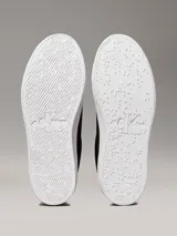 Zapatillas de ante negras con plataforma blanca y logo CK en el lateral.