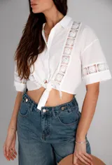 Camisa corta negra con detalles de encaje, de mangas cortas y anudada en la parte delantera.