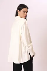 Camisa blanca de corte oversize, con cuello clásico y mangas largas con puños abotonados.