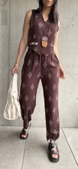 Conjunto de chaleco y pantalón color chocolate con estampado de rombos blancos. Chaleco con botones y pantalón de corte recto con elástico en la cintura y detalle de guarda pampa en el ruedo.