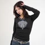 Remera negra de manga larga con estampado de cruz ornamentada en el centro del pecho.