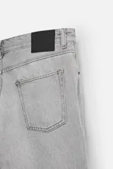 Pantalón de jean celeste de corte slim fit y tapered, con cinco bolsillos, efecto lavado y cierre frontal con cremallera y botón.
