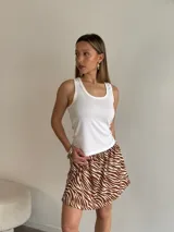 Pollera corta de jersey con estampado de cebra en tonos marrón y blanco. Presenta cintura fruncida y corte acampanado.