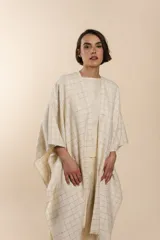 Ruana marrón con diseño a cuadros blancos, terminación envivada y flecos cortos.