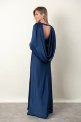 Vestido largo de satén de seda color azul con busto drapeado formando un nudo y capa que sale de los hombros.