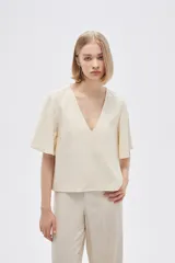 Blusa color crema de viscosa con escote en V y mangas cortas acampanadas.