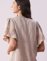 Blusa color beige de crepe, marca Batía, con cuello a la base y escote en V. Manga corta amplia con bordados.