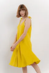 Vestido corto amarillo de lino, con escote en V y tirantes finos con detalle de moño en los hombros.