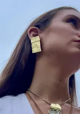 Aros colgantes rectangulares de metal dorado con textura irregular.