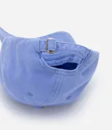 Gorra de sarga color lila con visera curva y bordado de una concha verde en el frente. Ajuste trasero con hebilla metálica.