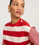 Remera de algodón con cuello redondo, cuerpo a rayas horizontales anchas verdes y blancas, y mangas cortas con rayas horizontales finas verdes y blancas. Presenta sisas desplazadas y costuras aparentes.