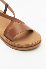 Sandalias marrones con tiras cruzadas y hebilla ajustable, suela de corcho.